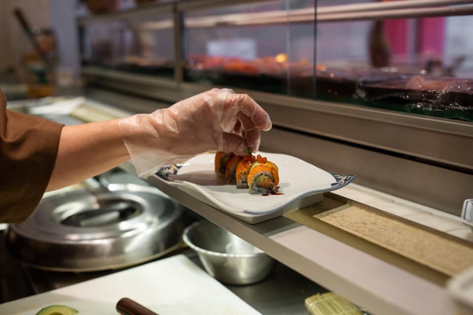 Chef placing golden leaf at top of special sushi piece with salmon caviar